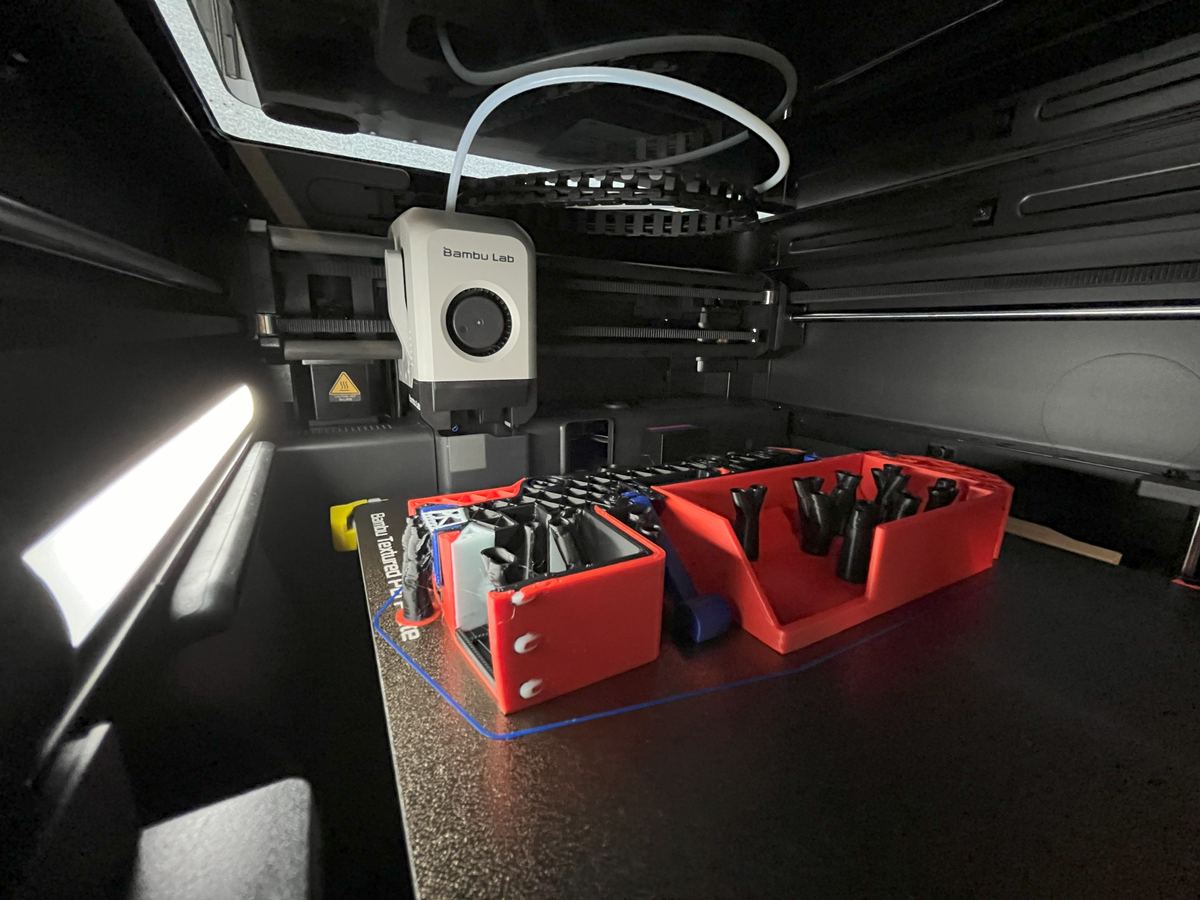 A Bambu Lab printer's build area filled with freshly printed parts